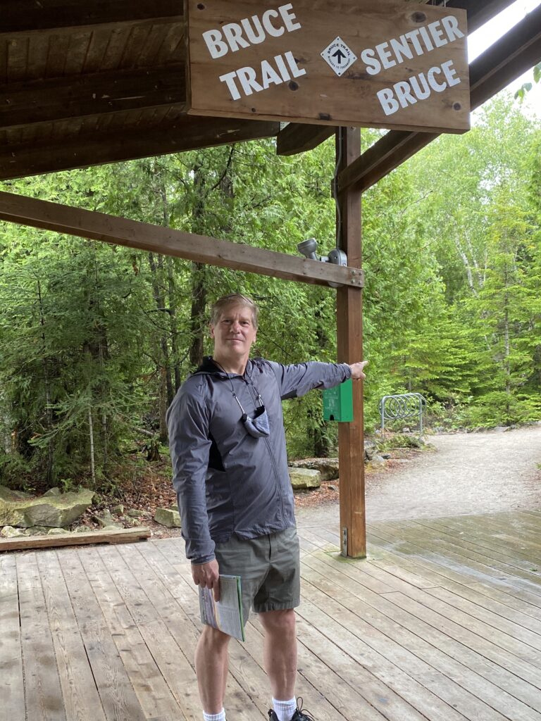 Man pointing at the start of a hiking trail, The Bruce Trail