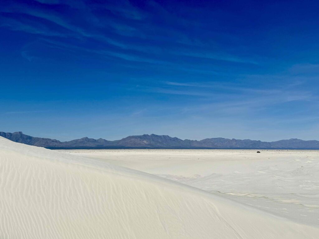 miles and miles of white sand with blue skies and mountain range in the background