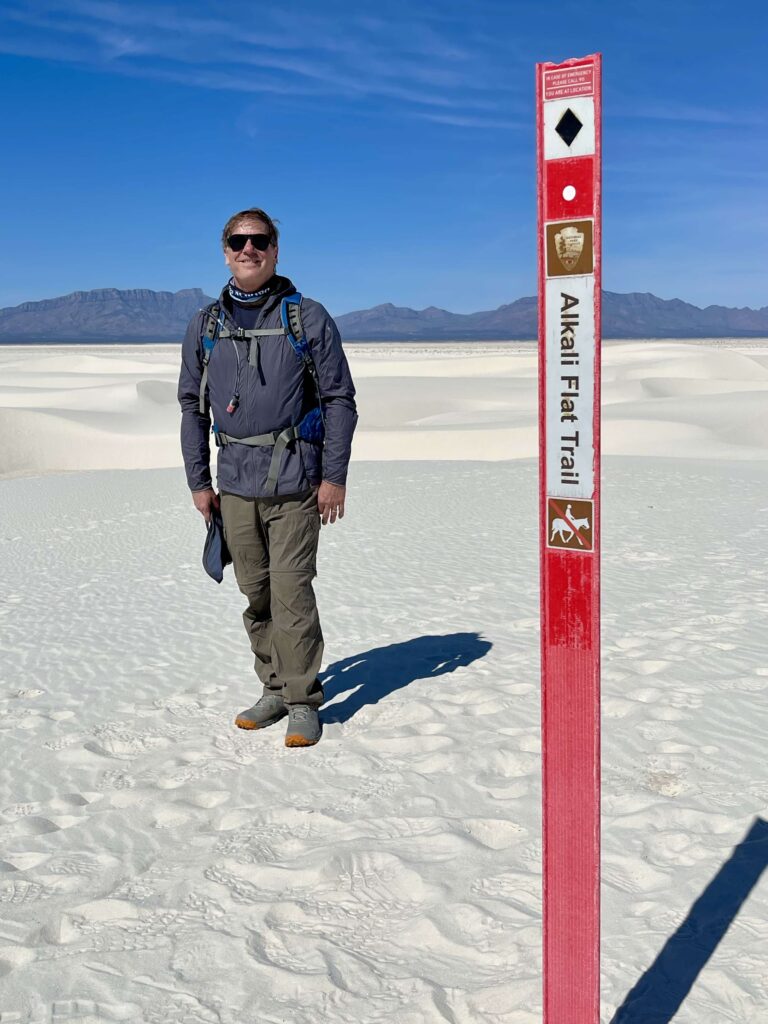 man standing in the desert with mountains in the background on the Alkali Flat Trail