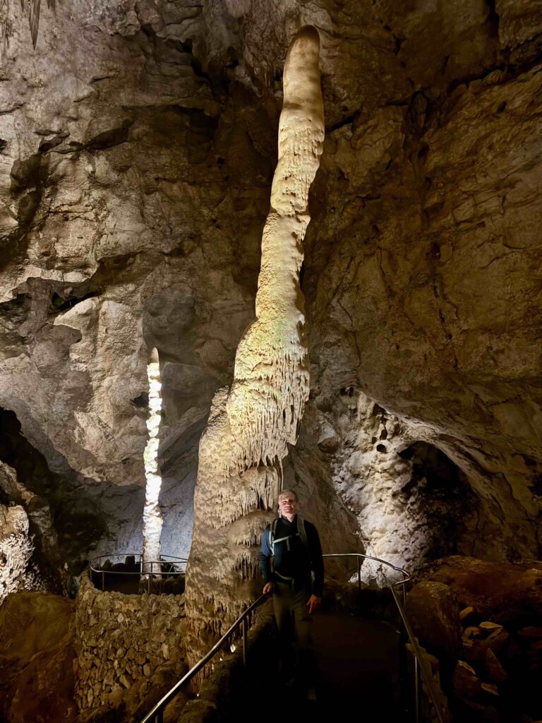 man standing in front of a large stalagmites