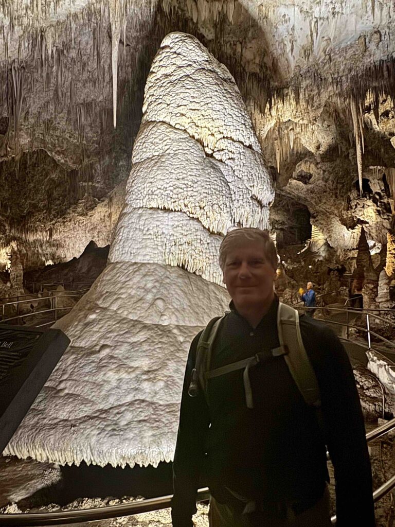 man standing in front of a large Stalagmite at carlsbad caverns national park