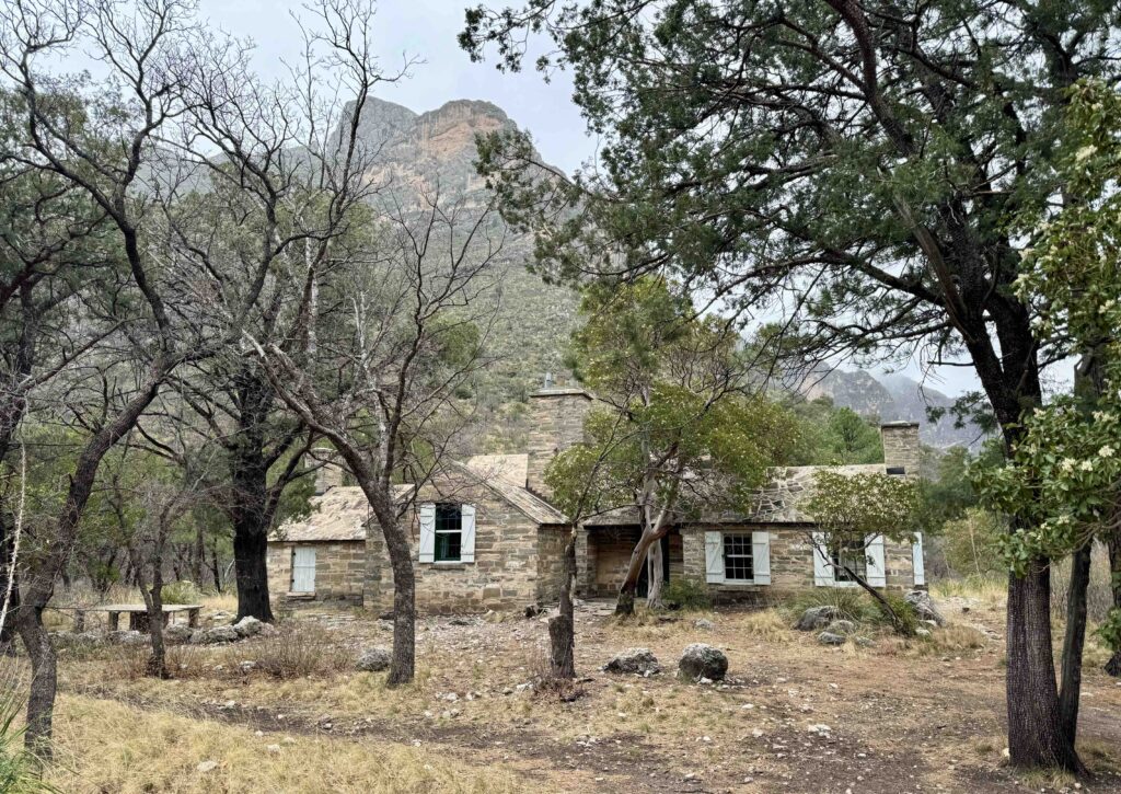 image of old stone cabin in a forest setting with a mountain in the background