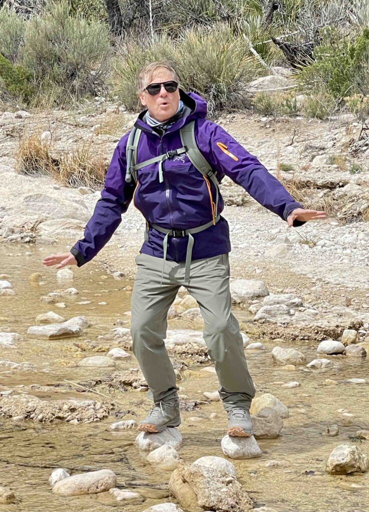 man balancing on two rocks in a river